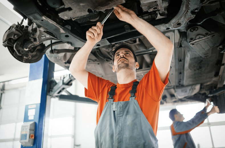 car mechanic checking under vehicle