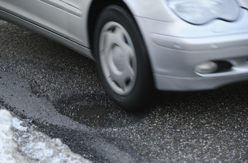 car driving over a pothole